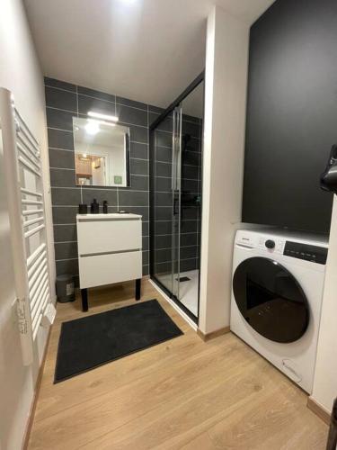 une salle de bain avec un lavabo et une machine à laver dans l'établissement L'Escale Paisible, entre dunes et plages, à Camiers