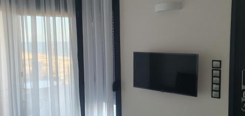 a flat screen tv on a wall next to a window at Boutique apartments Myesis in Samothráki