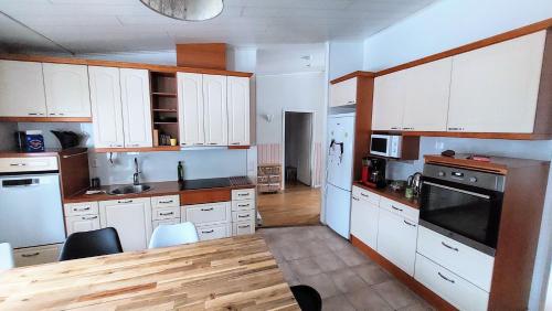 a kitchen with white cabinets and a wooden table at Tilava huone in Kerava