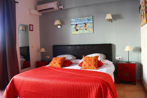 a bedroom with a bed with red and orange pillows at Hostal Don Peque Adult Recommended in Nerja