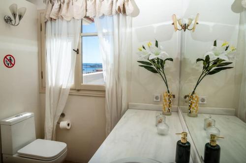 a bathroom with a toilet and a window with flowers at Portfront Neoclassical Gem in Lavrio in Lávrion