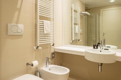a bathroom with two sinks and a toilet and a mirror at UNA HOTELS Le Terrazze Treviso Hotel & Residence in Villorba
