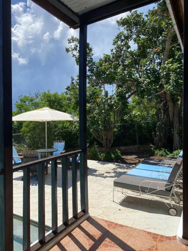 a patio with a lounge chair and an umbrella at Bliss By The Sea - Beach Front Villa with Private Pool in Treasure Beach