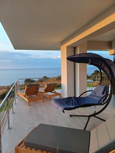 a balcony with chairs and an umbrella and the ocean at Boutique apartments Myesis in Samothráki