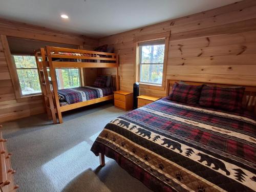 a bedroom with two beds in a log cabin at Scoot Cabin - Dogs Welcome! in Carrabassett