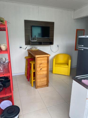 a kitchen with a tv and a table and a yellow chair at Pousada da Vovó Ideni Nova Tramandaí in Tramandaí