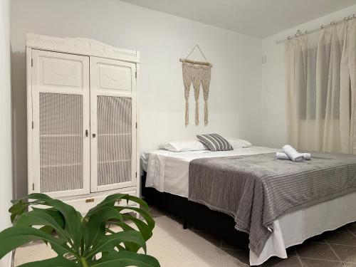 a bedroom with a bed and a wardrobe and a plant at Apartamento amplo e confortável 1 in Maringá