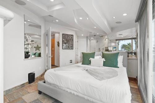 a white bedroom with a large bed with green pillows at Stunning Oceanfront Boardwalk Condo - Spa, Steps2Beach, Parking & Fast Wifi! in San Diego