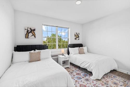 two beds in a white room with a window at Supreme 2 Bedroom Condo in Prime Jersey City in Jersey City