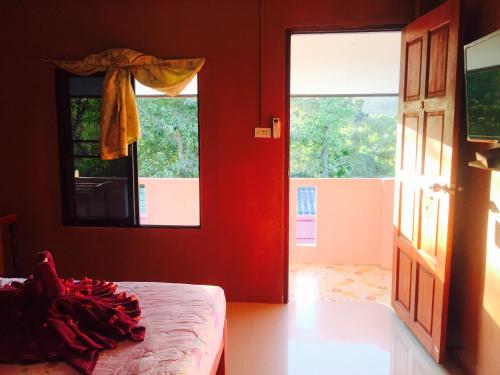 a bedroom with red walls and a bed and a window at Miss Tim House in Ko Samed