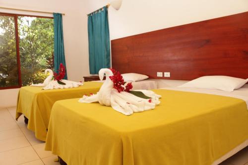 two beds in a hotel room with yellow tables at Piedras Blancas Lodge in Puerto Ayora