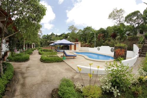 um quintal com uma piscina, um banco e um guarda-sol em Piedras Blancas Lodge em Puerto Ayora