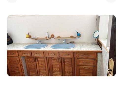 Un baño con dos lavabos y armarios de madera. en APPARTEMENT MEUBLE, Proche PARIS PROCHE DISNEY, en Neuilly-sur-Marne