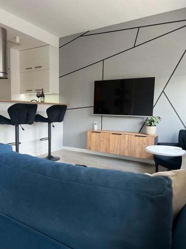 ein Wohnzimmer mit Fernseher und blauem Sofa in der Unterkunft Pomorska Apartment in Breslau