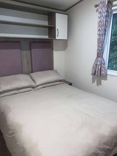 a bedroom with a white bed and a window at Kiln Park in Tenby