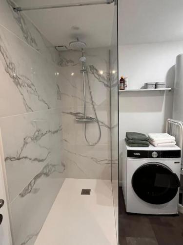 une salle de bain blanche avec douche et micro-ondes dans l'établissement Le Castelnau, à Linselles