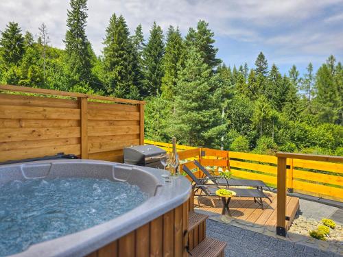 a hot tub on a deck with a wooden fence at LK Mountain Residence segmenty z prywatnym jacuzzi i widokami na góry i jezioro in Falsztyn