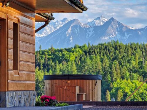 a wooden building with mountains in the background at LK Mountain Residence segmenty z prywatnym jacuzzi i widokami na góry i jezioro in Falsztyn