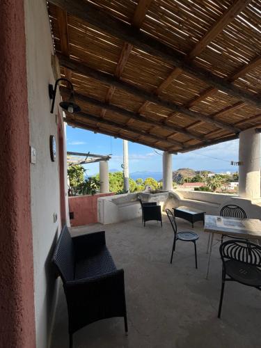 a patio with chairs and tables and a wooden roof at Villa La Rosa in Filicudi
