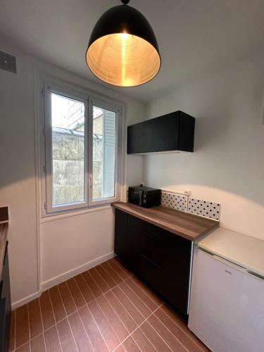 une cuisine avec un comptoir et une fenêtre dans l'établissement Appartement calme près de La Villette, à Paris