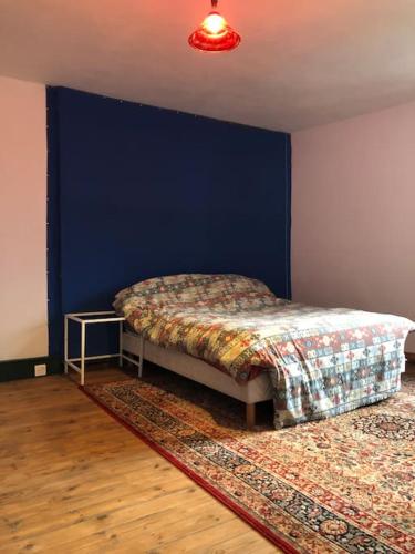 une chambre avec un lit avec un mur bleu dans l'établissement Maison Bourgeoise années 50, à Haybes