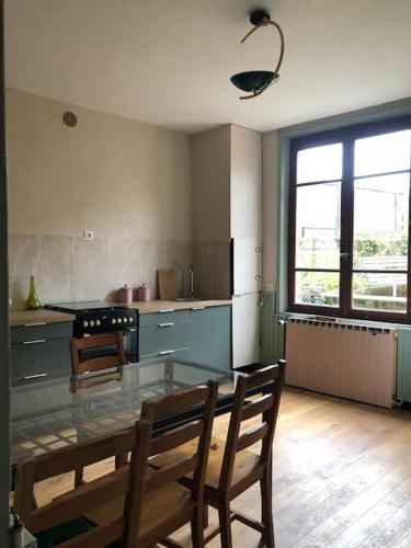 une cuisine avec une table en verre et des chaises. dans l'établissement Maison Bourgeoise années 50, à Haybes