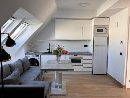 フエンヒロラにあるNew Central & Cosy Apartments at Fuengirola Beachの白いキャビネットと花のテーブル付きのキッチンが備わります。