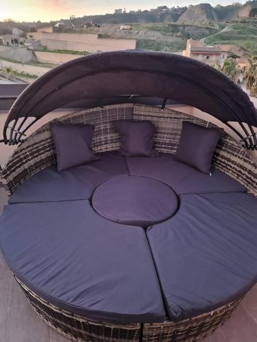 a wicker bed with purple pillows on a balcony at Romantico monolocale veranda privata vista mare in Reggio Calabria