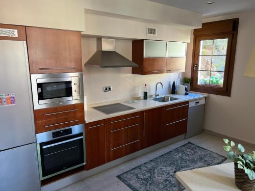 a kitchen with wooden cabinets and a sink and a microwave at La Villa de Herce in Herce