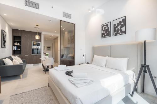 a bedroom with a large white bed and a living room at Free housekeeping visits during your stay - StayShort - Awesome Studio at Park View Tower in JVC with Skyline Views in Dubai