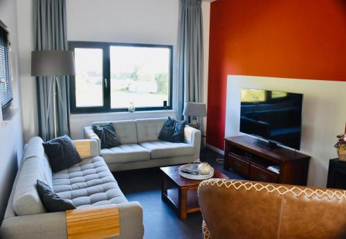 a living room with a couch and a tv at De Toffe Peer Recreatie in Ruinerwold
