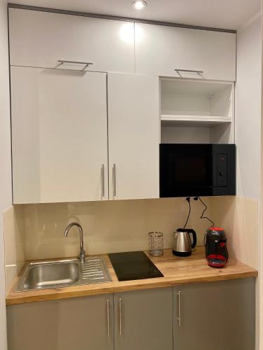 a kitchen with white cabinets and a sink at Zielona Ostoja - Pokoje i Apartamenty in Nowa Sarzyna