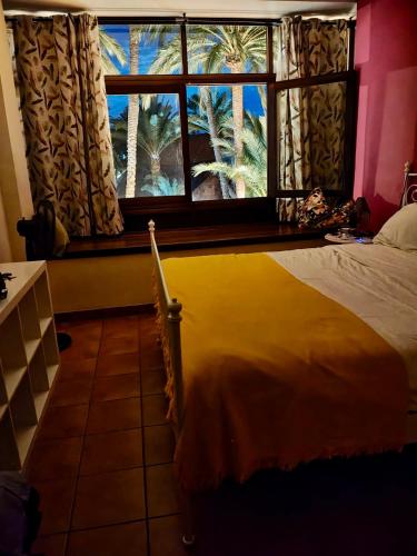a bedroom with a large window with palm trees at LOS FRAILES I in San Sebastián de la Gomera