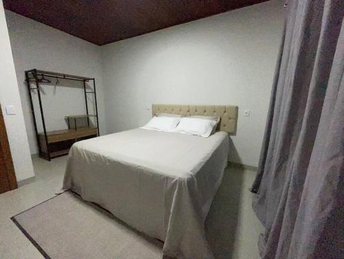 a bedroom with a white bed and a mirror at Casa Ampla Jd Primaveras in Sinop