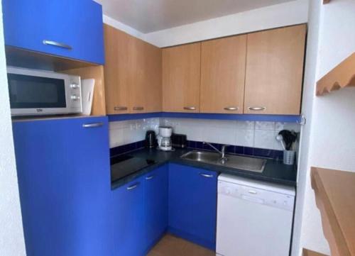 - une cuisine bleue avec évier et four micro-ondes dans l'établissement Appartement T2 au pieds des pistes, Les Orres 1800, aux Orres