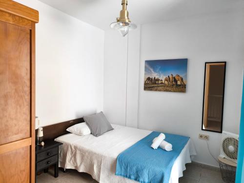 ein Schlafzimmer mit einem Bett mit einer blauen Decke in der Unterkunft Acogedoras Habitaciones Privadas zona Costera Wifi in Morro del Jable