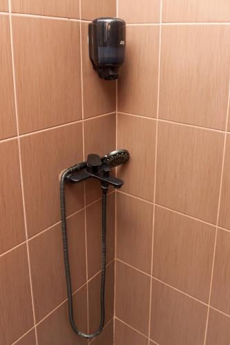 a shower with a hose on a tiled wall at Red Clay Apartments City Club in Belgrade