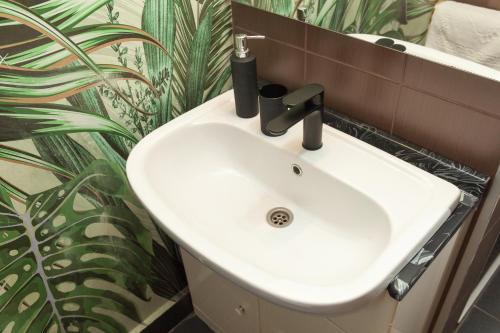 a white sink in a bathroom with a plant at Red Clay Apartments City Club in Belgrade
