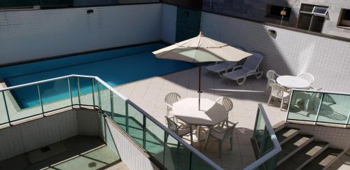 una piscina con tavolo e ombrellone di Apartamento Premium Praia do Forte a Cabo Frio