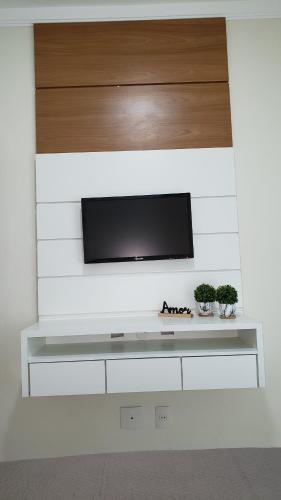 una TV a schermo piatto a parete con due piante di Apartamento Premium Praia do Forte a Cabo Frio