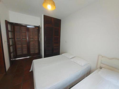 a white room with two beds and a window at SUÍTES NA PRAIA DO ITAGUÁ conchegouba in Ubatuba