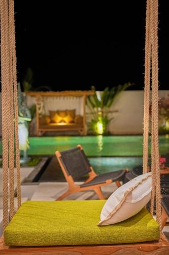 a swing with a green cushion and a chair at Kamalie Bali Luxury in Tanah Lot