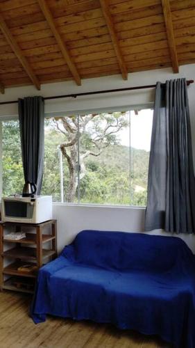 a bedroom with a blue bed and a window at Mini Casa in Baependi
