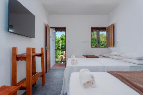 a bedroom with two beds and a tv on the wall at Pousada Trilha do Mar in Praia do Frances