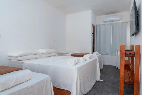 a white room with two beds and two tables at Pousada Trilha do Mar in Praia do Frances