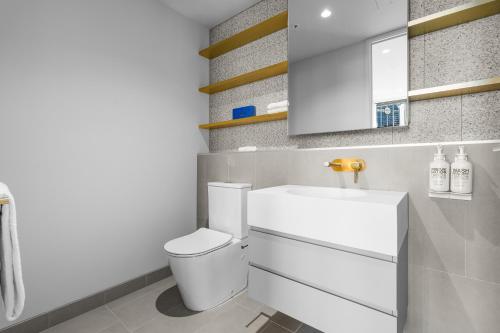 a white bathroom with a toilet and a sink at Paragon Apartments by CLLIX in Melbourne