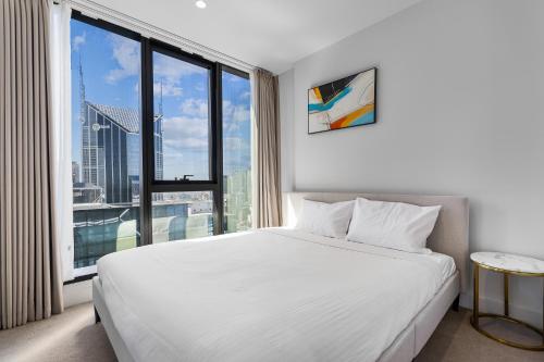 a bedroom with a white bed and a large window at Paragon Apartments by CLLIX in Melbourne
