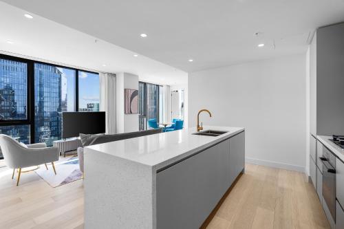 a kitchen with white countertops and a living room at Paragon Apartments by CLLIX in Melbourne