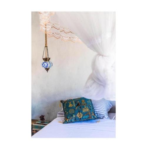 a bed with a blue pillow and a white curtain at Suíte Istambul Villas de São Jorge in Trancoso