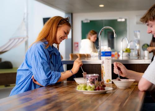 a woman is standing at a table eating food at LyLo Christchurch Airport in Christchurch